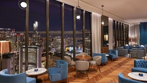 Un moderno vestíbulo de hotel con vistas panorámicas de la ciudad, asientos cómodos y un suelo de madera en espiga.