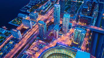 An aerial view of a cityscape with high-rise buildings, roads, and a stadium.