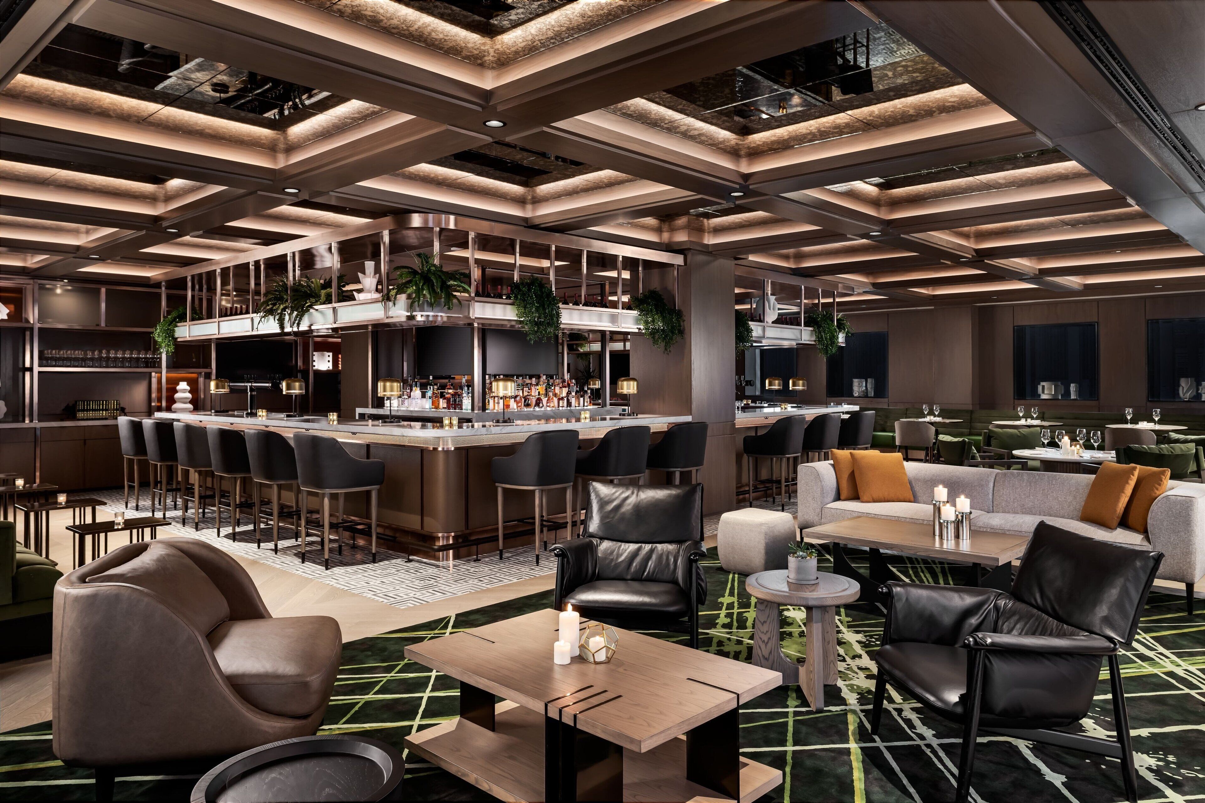 A modern hotel lobby with a bar area, seating arrangements, and a high ceiling with exposed beams.