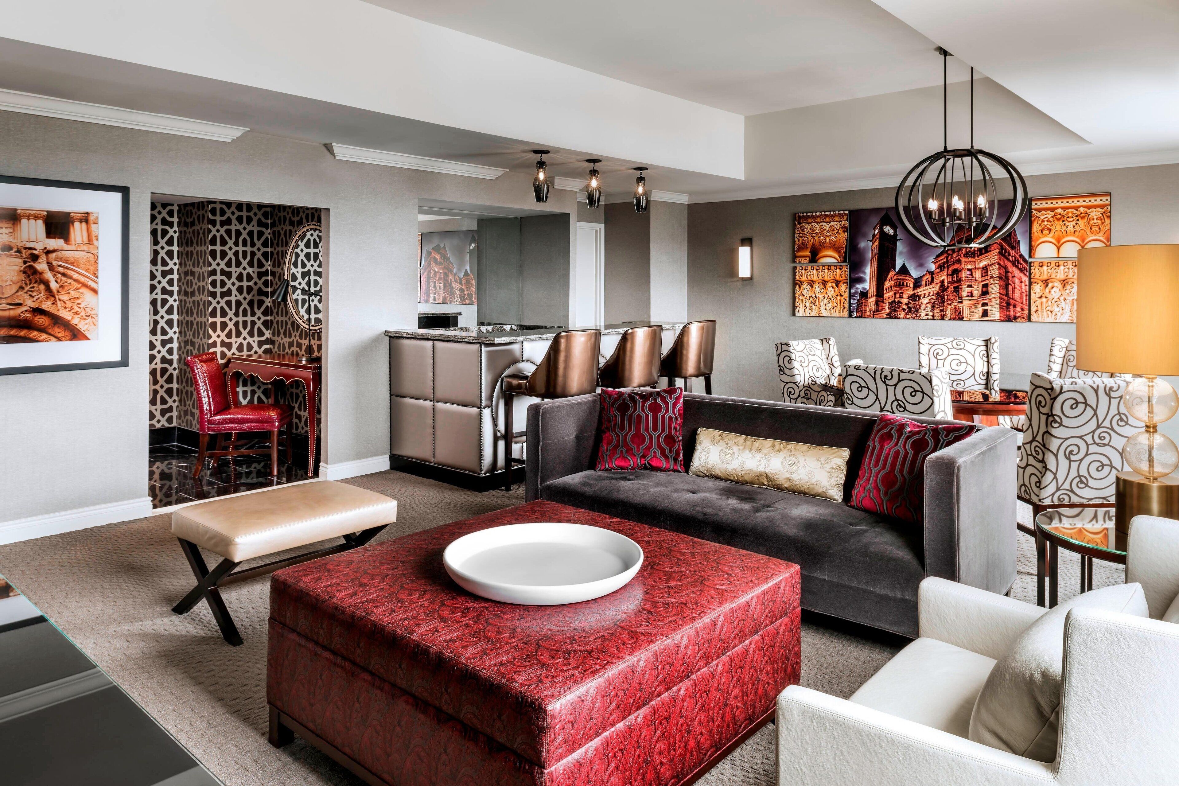 A modern living room with a sofa, ottoman, and a dining area with chairs.