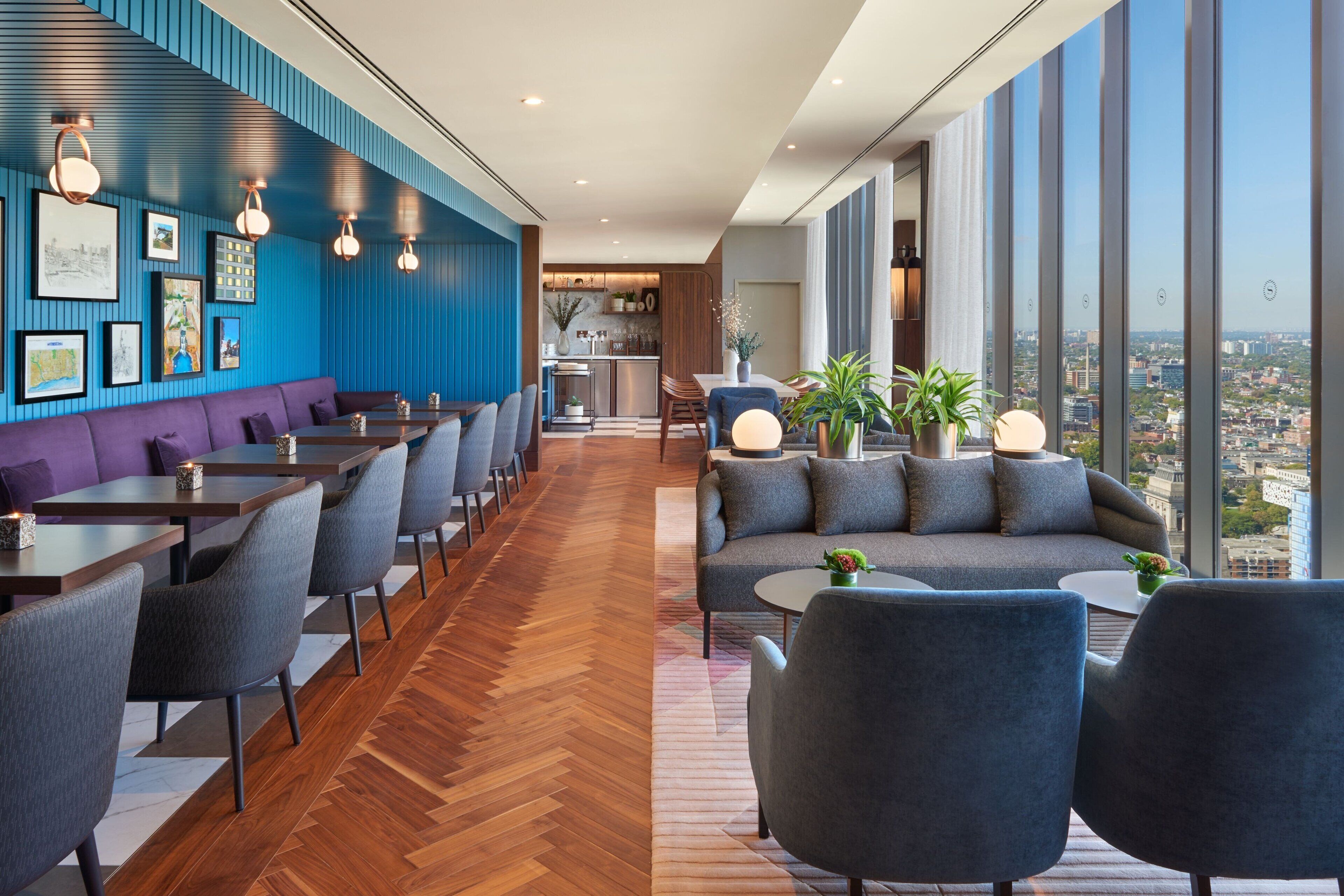 A modern hotel lobby with a dining area, seating, and a view of the city.