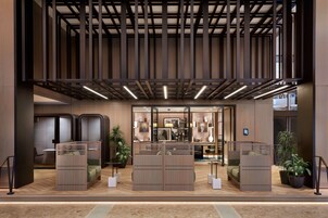 Een moderne hotellobby met een hoge plafond, houten lambrisering en een receptiebalie.