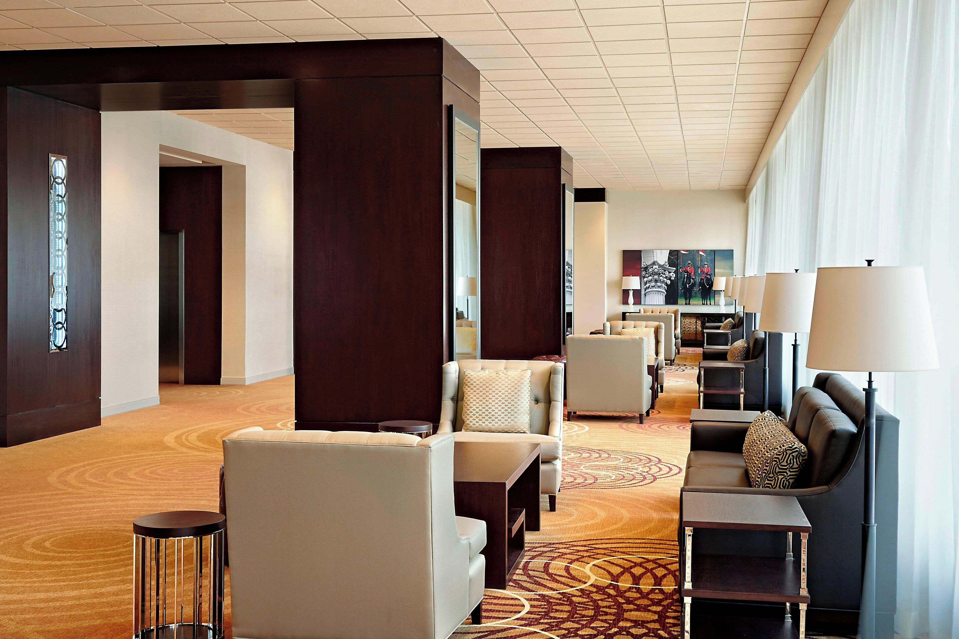 Un hall de hotel con zonas de estar, un mostrador de recepción y un ventanal grande que proporciona luz natural.