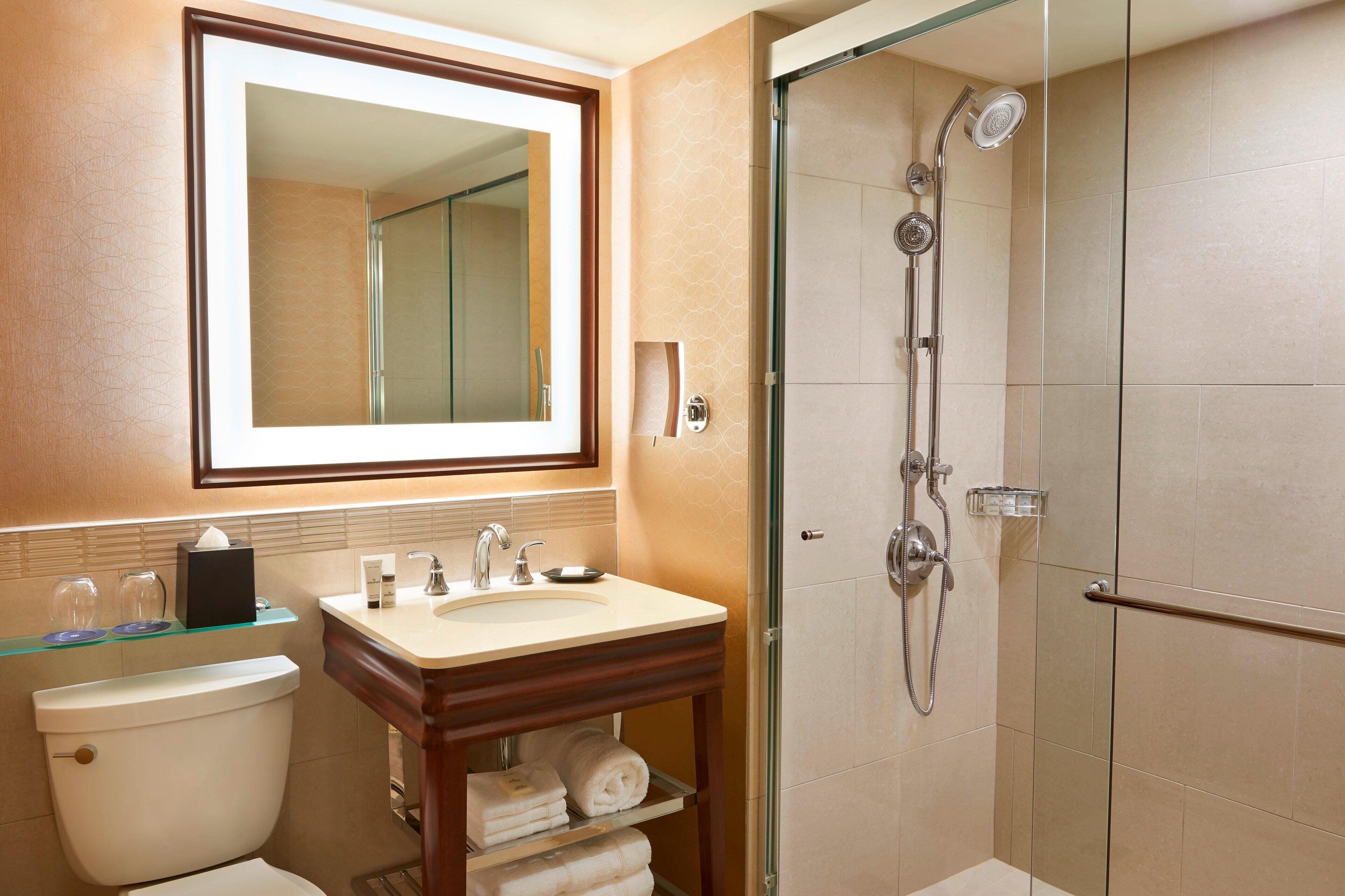 Een badkamer met toilet, wastafel, spiegel en douchecabine.