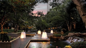 A serene garden with a pond, illuminated tables, and a waterfall. - Sheraton Centre Toronto Hotel (Toronto)