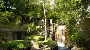 Una cascada en un jardín ajardinado con muros de piedra y plantas en macetas.