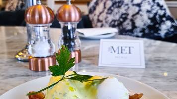 Een ontbijtje met eggs benedict, spek en hollandaisesaus, afgeleid met een takje peterselie.