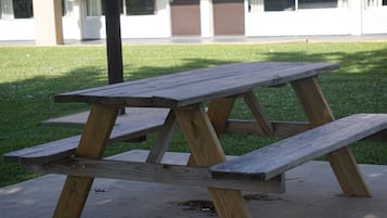 Uma mesa de piquenique de madeira com bancos, apoiada em uma superfície de concreto em uma área gramada.