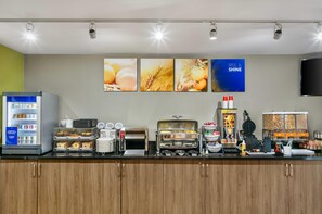 A breakfast bar with a refrigerator, toaster, waffle maker, and various food containers.