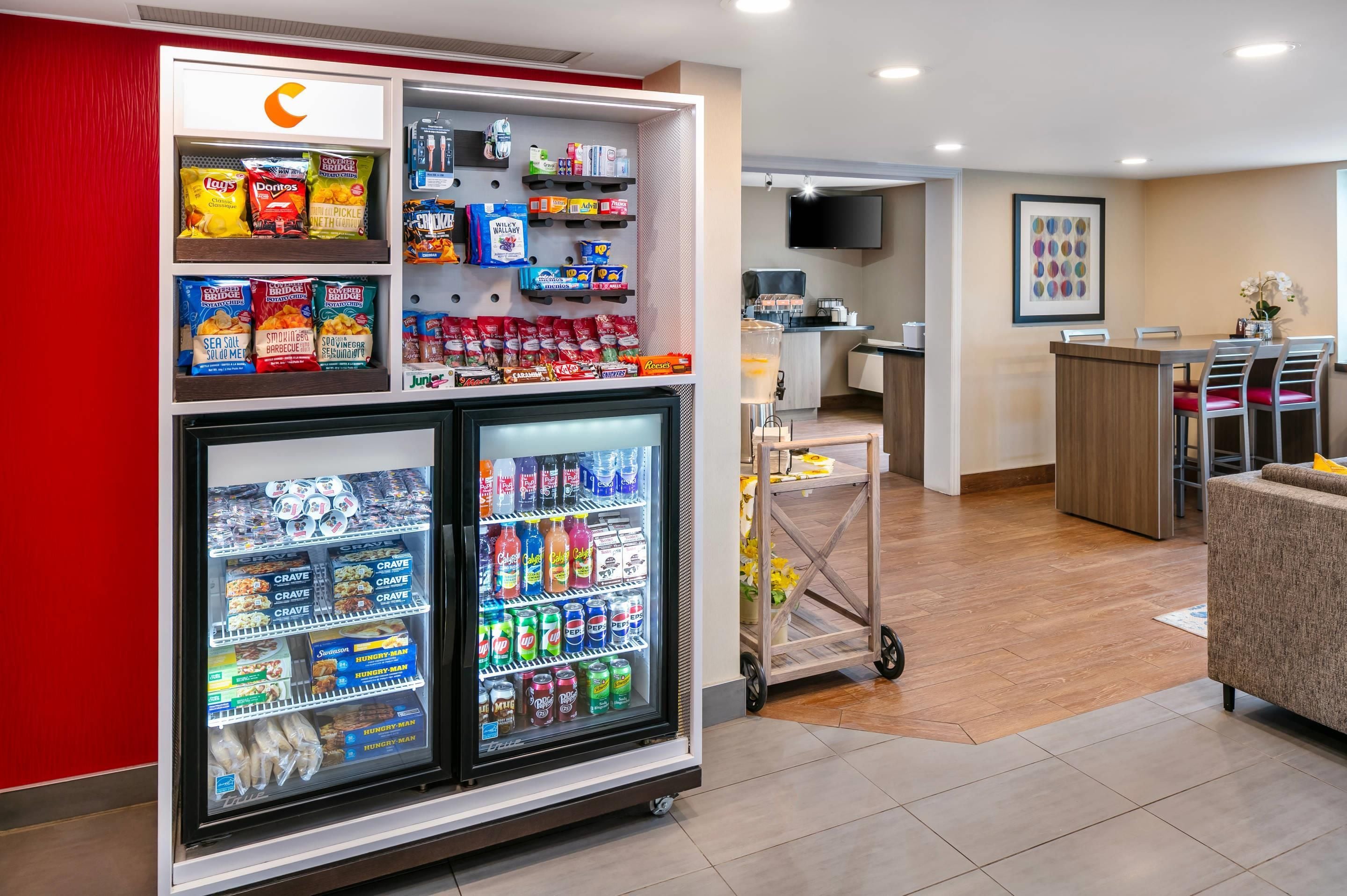 A hotel lobby with a self-service snack bar stocked with chips, candy, and beverages.