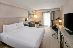 Una camera d'albergo con un letto grande, una scrivania con una sedia, una televisione e un quadro appeso al muro.