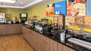 A breakfast buffet with various food options, a coffee machine, and a self-serve beverage station. - Comfort Inn Truro (Lower Truro)