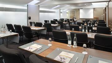 A conference room with multiple tables, chairs, and water bottles.