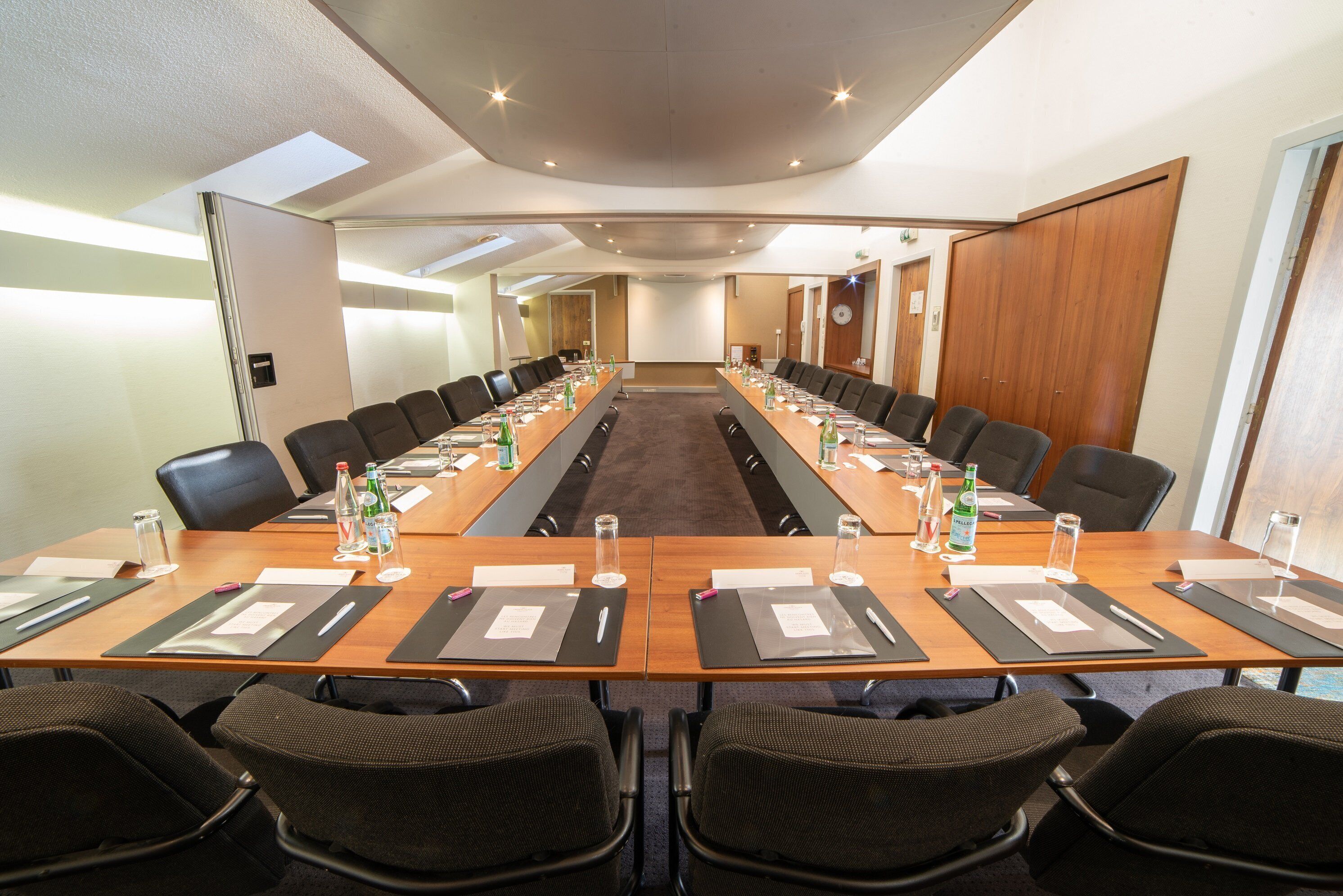 A conference room with a long table, multiple chairs, and water bottles.