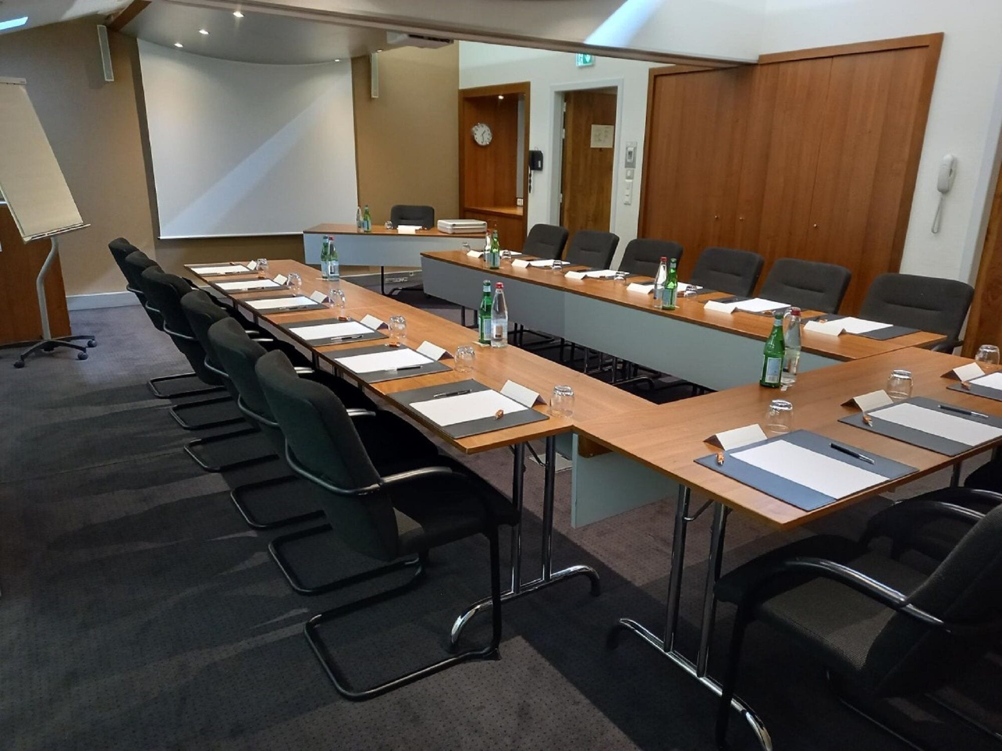 A conference room with a long table, black chairs, and water bottles.