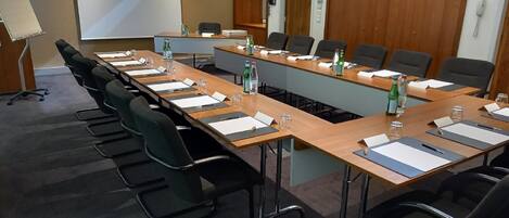 A conference room with a long table, black chairs, and water bottles.