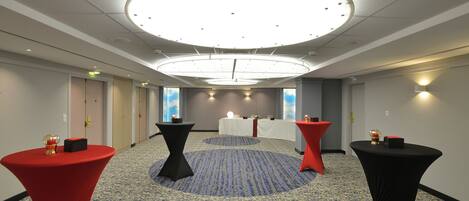 A conference room with a circular ceiling light, a carpeted floor, and a table with a red tablecloth.