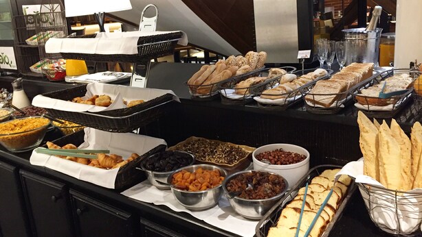 Un bufé con diferentes opciones de comida, incluyendo pan, pasteles y frutas.