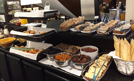 A buffet with various food items including bread, pastries, and fruits.