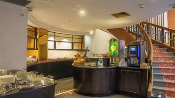 A modern kitchen with a curved counter, a coffee machine, and a fruit display.