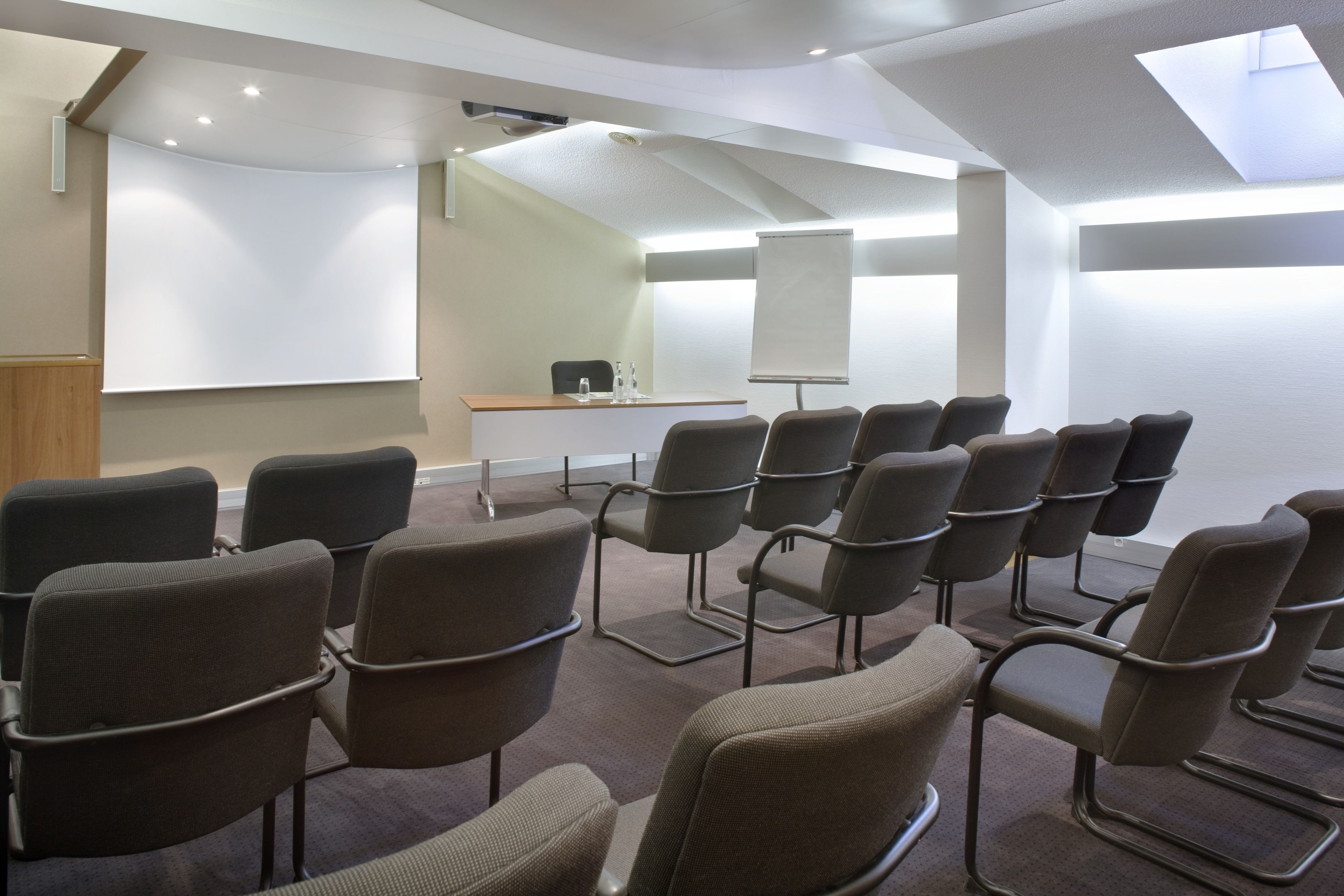 A conference room with a whiteboard, a podium, and several chairs arranged in rows.