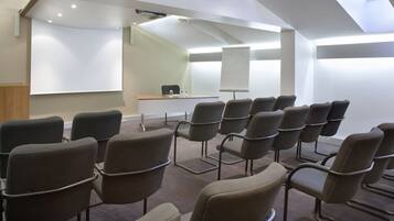 A conference room with a whiteboard, a podium, and several chairs arranged in rows.