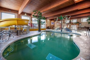 Una piscina interior con toboganes, una cascada y un área de estar con mesas y sillas.