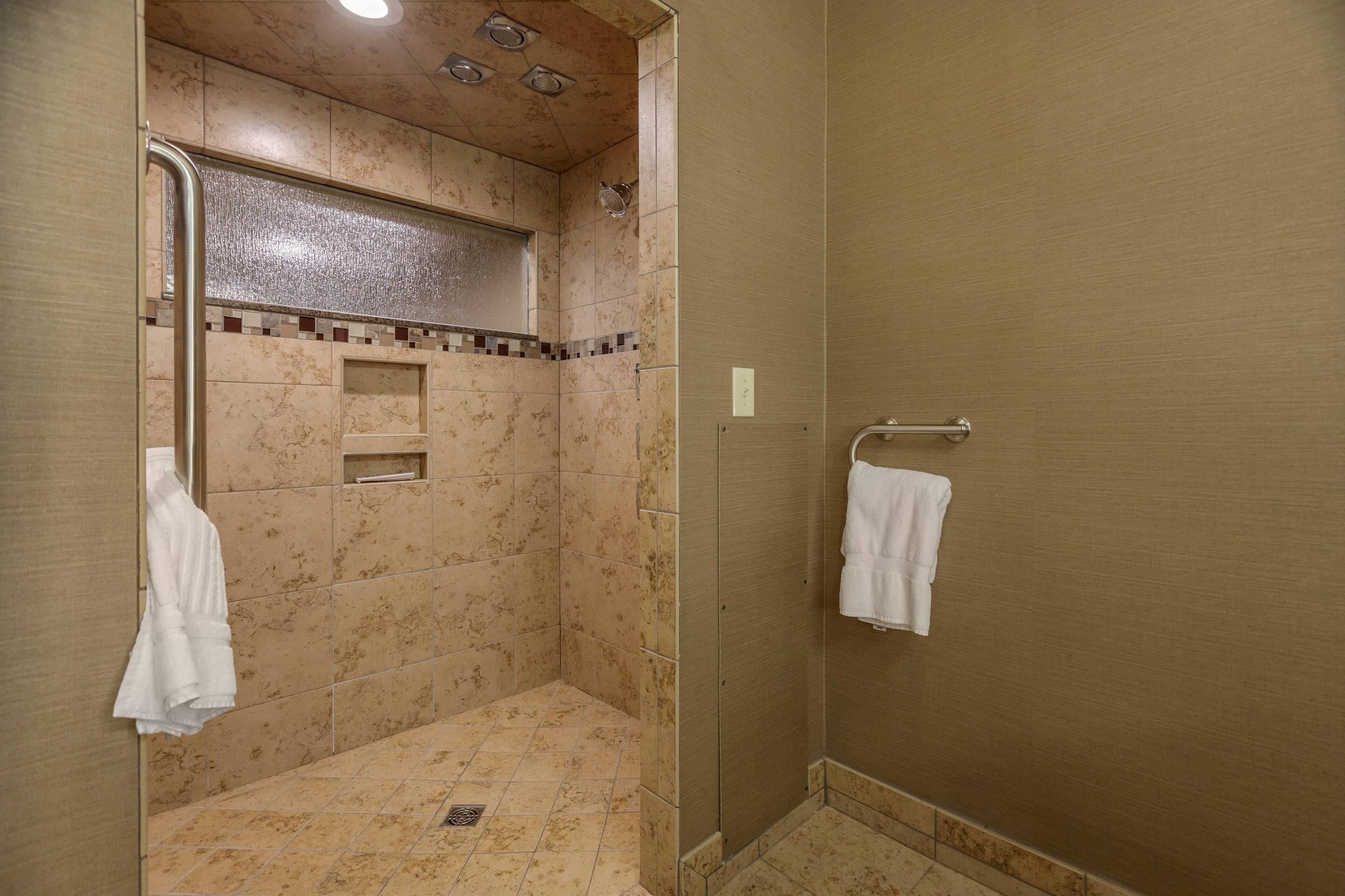 A shower area with a glass door, a towel rack, and a showerhead.