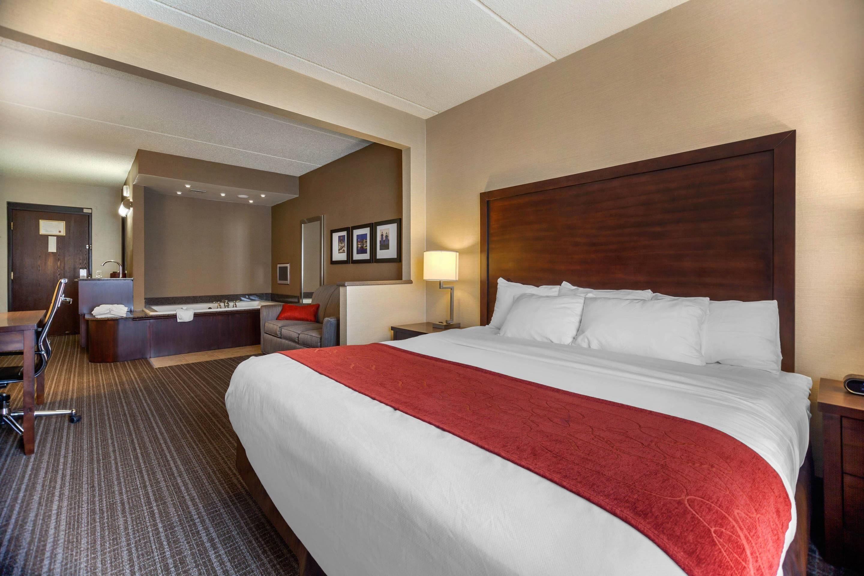 Ein Hotelzimmer mit einem großen Bett, einem Schreibtisch mit Stuhl, einer Sitzecke und einem Badebereich.