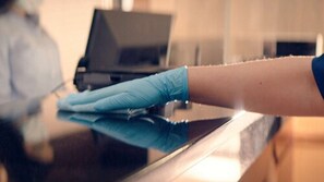 A person wearing a blue glove cleaning a shiny black surface, likely a counter or table.