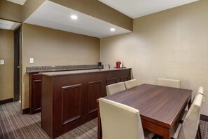 A conference room with a wooden table and chairs, a kitchenette with a coffee maker, and a door leading to another room. - Comfort Suites Green Bay West (Green Bay)
