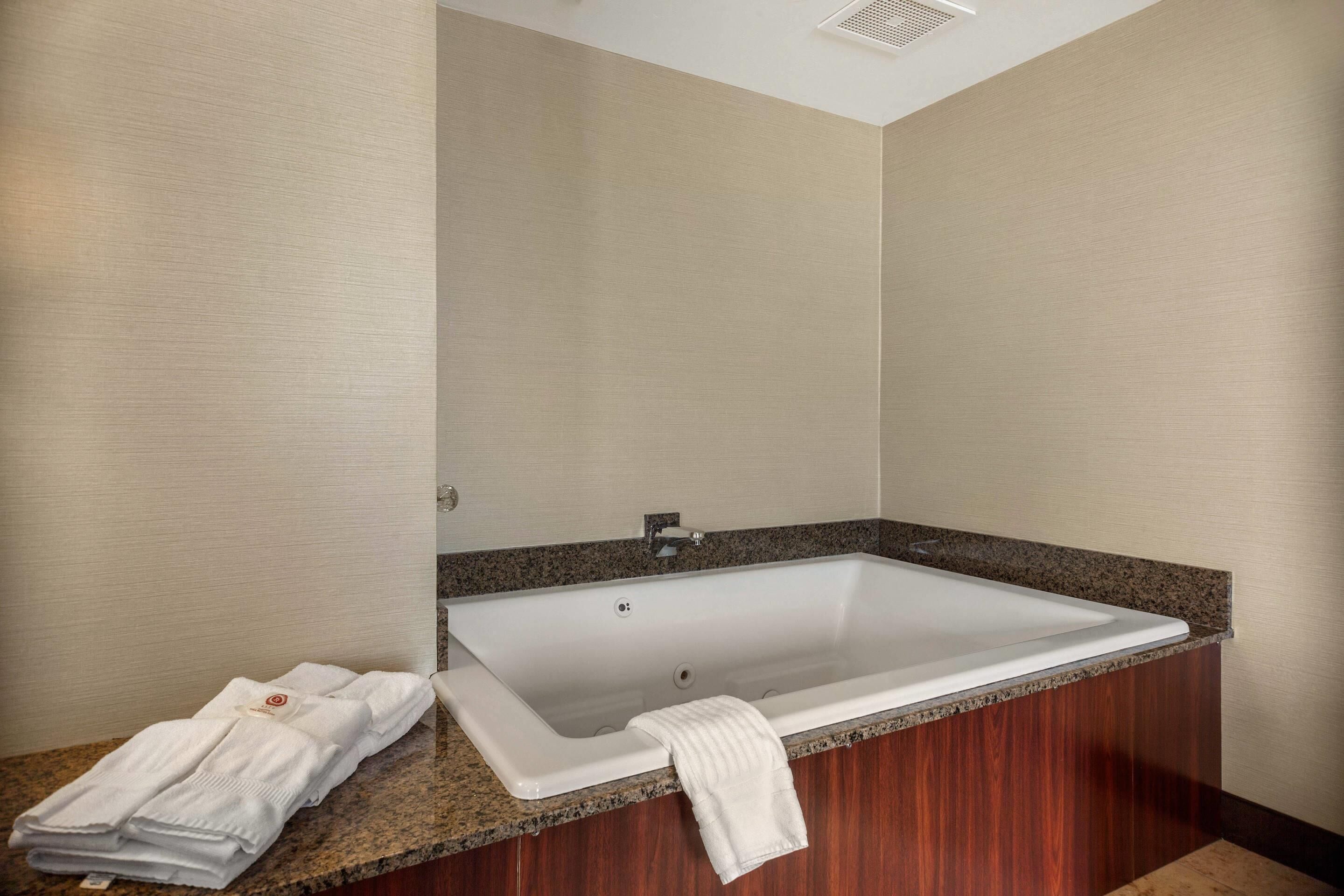 A modern bathroom with a freestanding bathtub, a granite countertop, and a towel rack with folded towels.