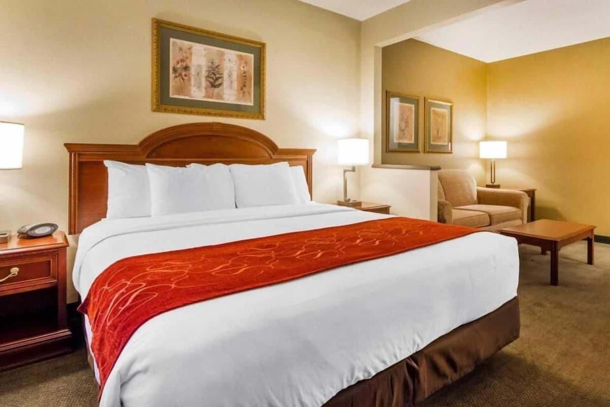 Een hotelkamer met een groot bed, twee nachtkastjes, een stoel en een bureau.