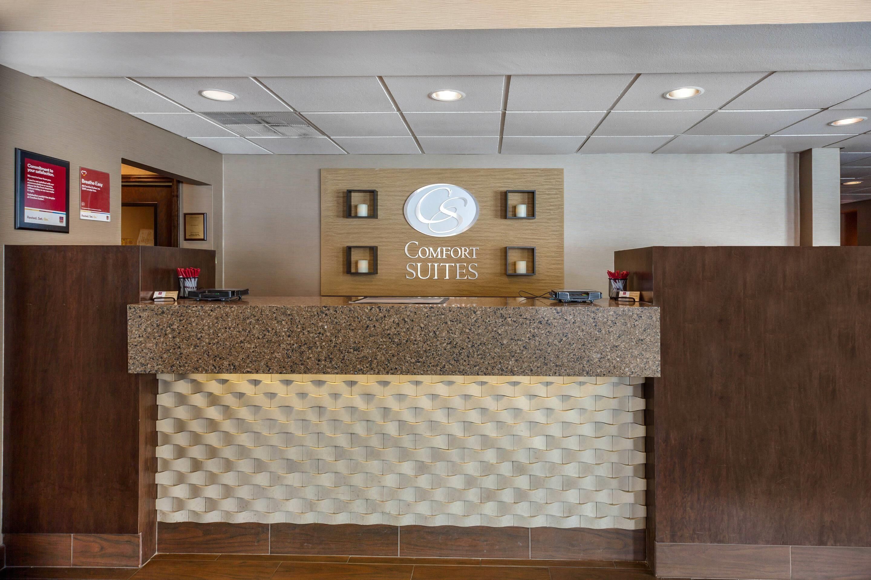 A reception desk with a sign that reads 'COMFORT SUITES' and a logo above it.