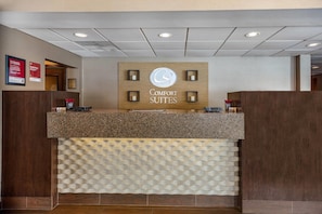 A reception desk with a sign that reads 'COMFORT SUITES' and a logo above it. - Comfort Suites Green Bay West (Green Bay)