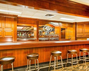 A bar area with wooden cabinets, a counter, and bar stools.