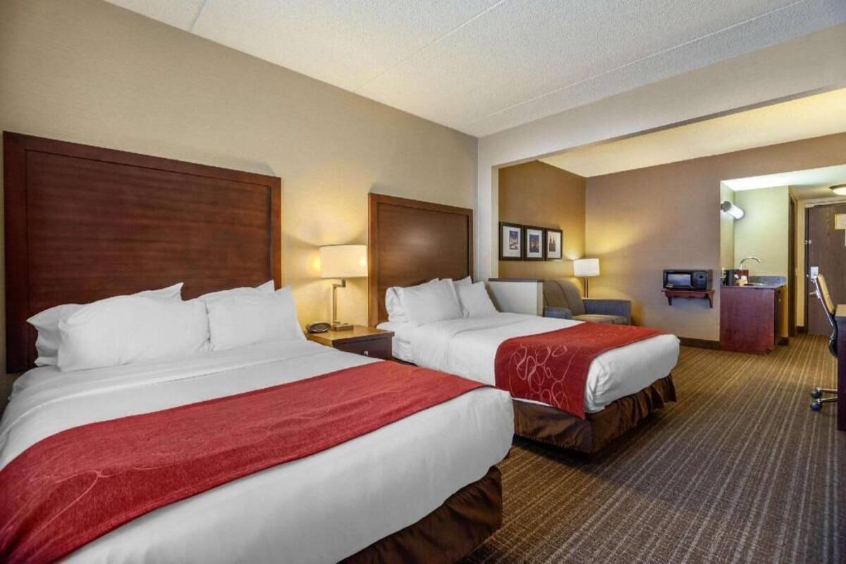 Een hotelkamer met twee bedden, een bureau, een stoel, een televisie en een badkamer.
