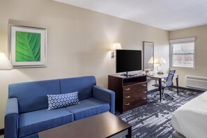 A hotel room with a blue sofa, a desk with a computer, a flat-screen TV, and a bed. - Best Western Owego Inn (Owego)