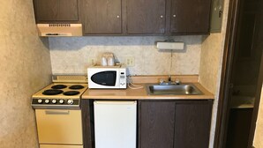 Una cocina compacta con estufa, microondas, lavavajillas y pileta.