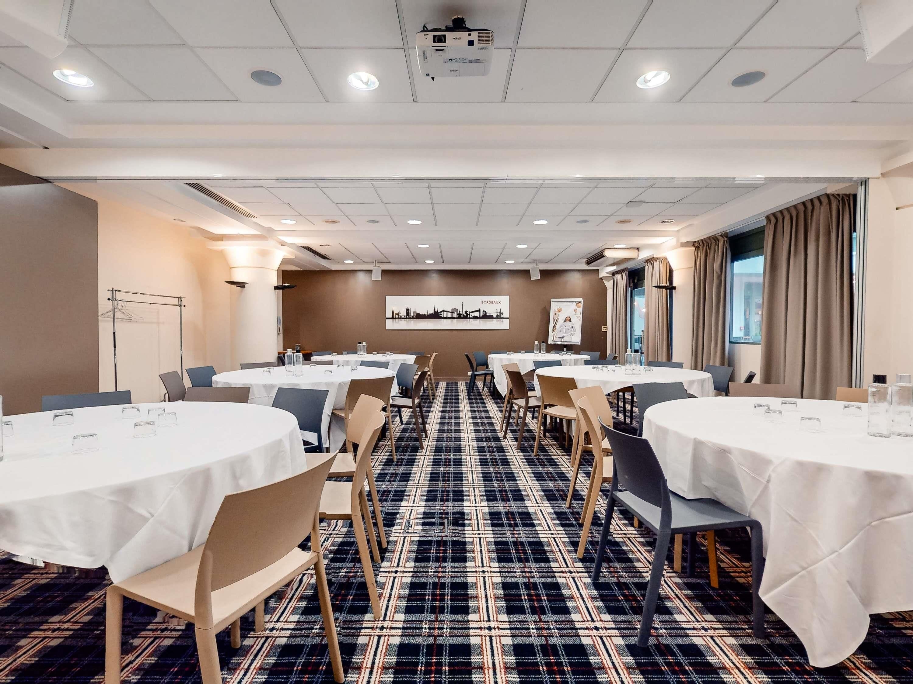 A conference room with round tables, chairs, and a patterned carpet.