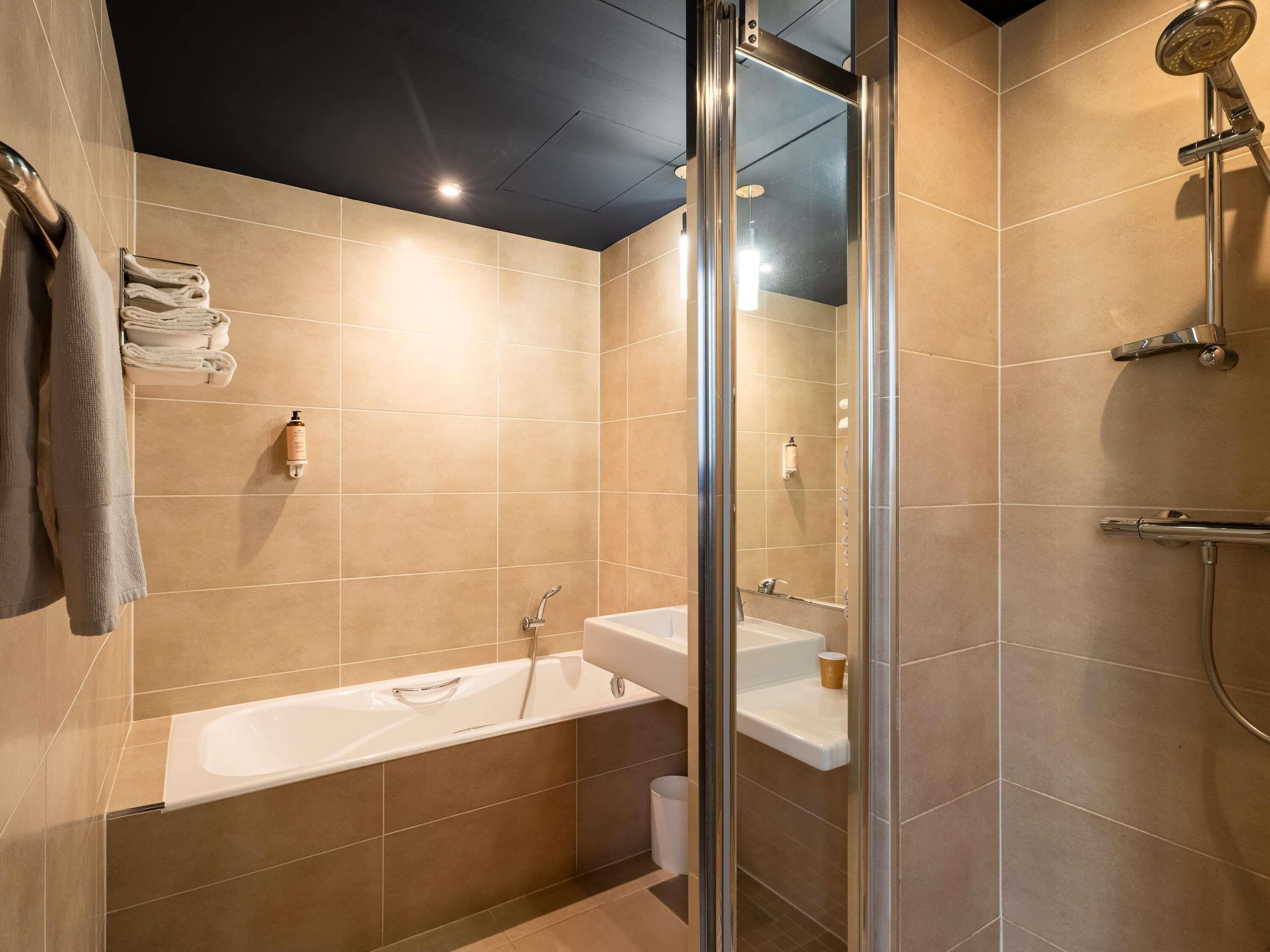 A modern bathroom with a glass-enclosed shower, a built-in sink, and a bathtub.