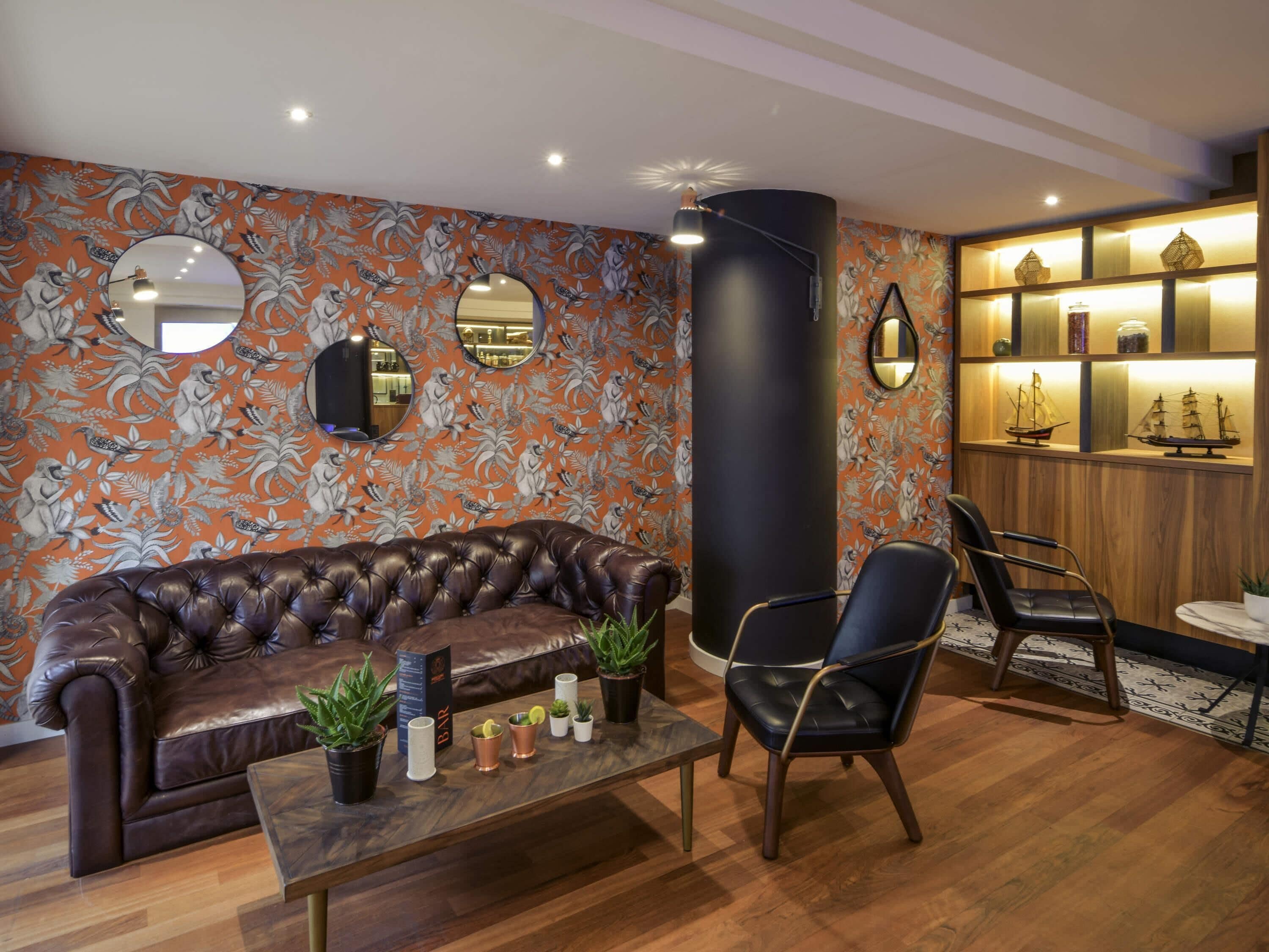Una sala de estar moderna con un sofá de cuero, una mesa de centro con plantas y un mueble de madera con adornos.