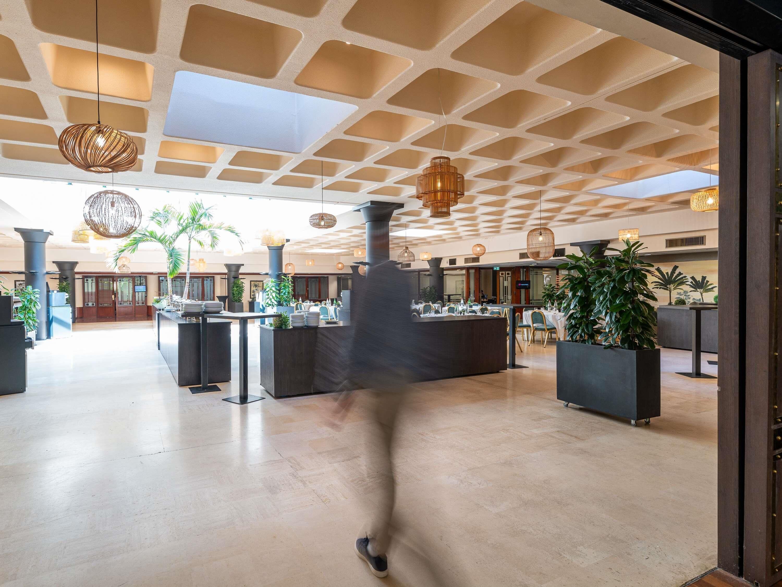 A spacious lobby with a high ceiling, modern lighting fixtures, and a central reception desk.