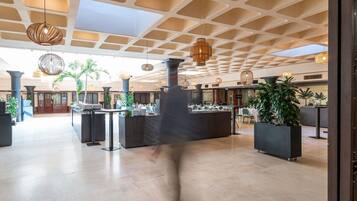 Un hall d’entrée spacieux avec un plafond haut, des luminaires modernes et un comptoir d’accueil central.