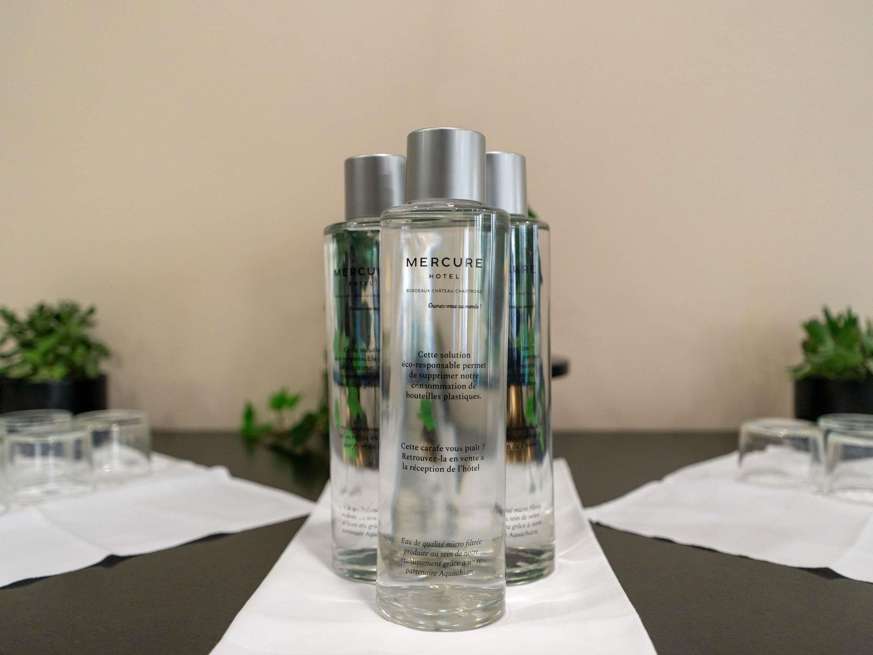 Three bottles of MERCURE hotel water on a table with white napkins.
