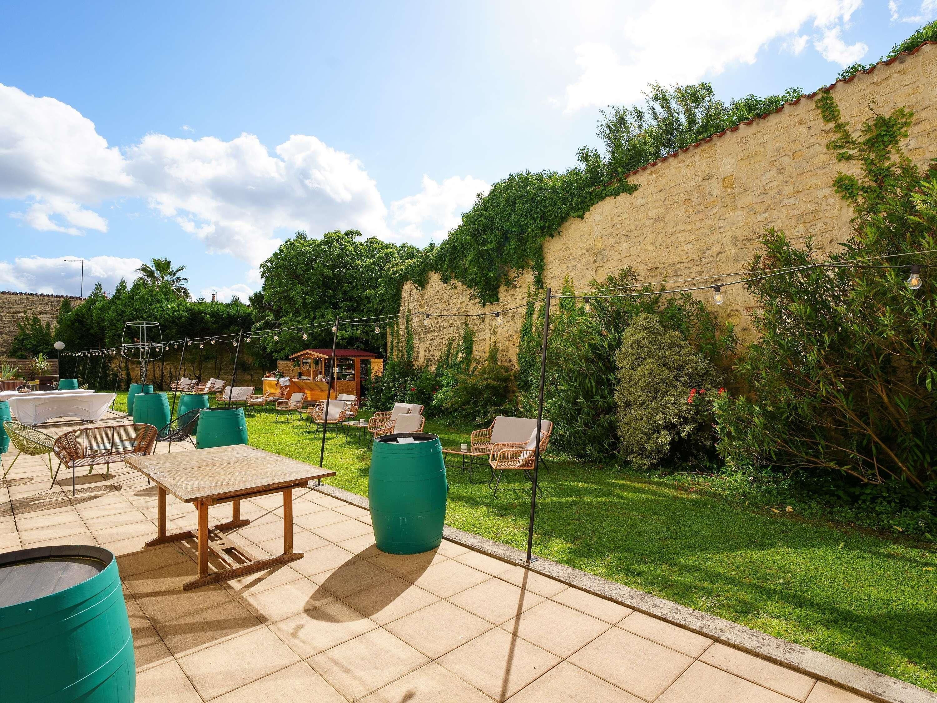 An outdoor patio with tables and chairs, a bar area, and a stone wall.