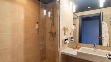 A modern bathroom with a glass-enclosed shower, a white sink, and a mirror with a blue door in the background.