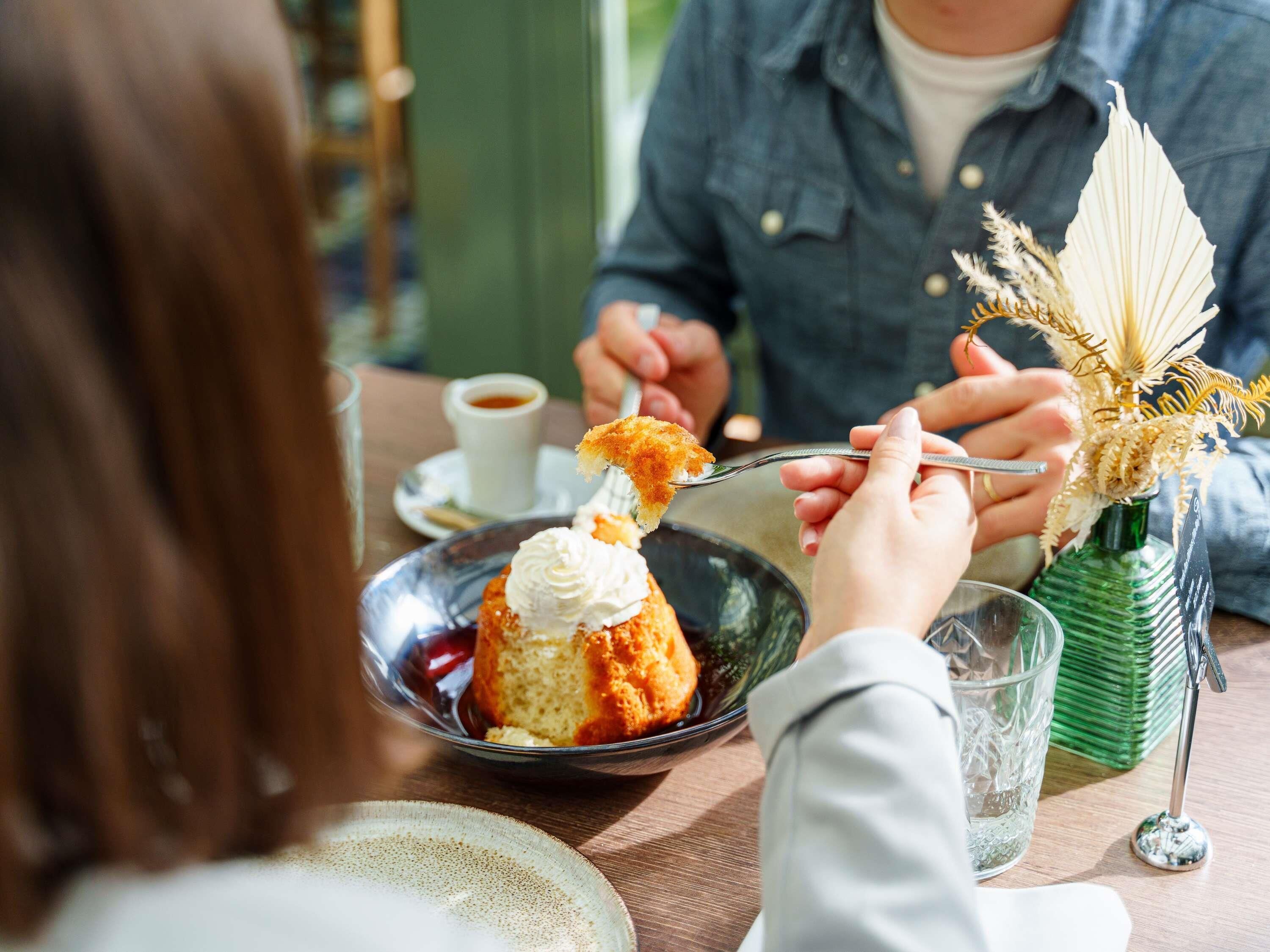Una mesa de comedor con un plato de postre, una taza de café y un jarrón decorativo.