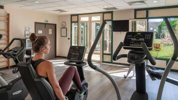 A gym with cardio machines, a clock, and a view of the outdoors.