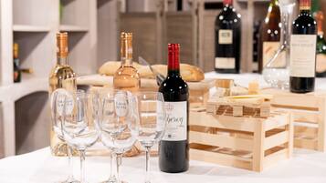 Une table avec des verres à vin et des bouteilles, une caisse en bois et du pain.